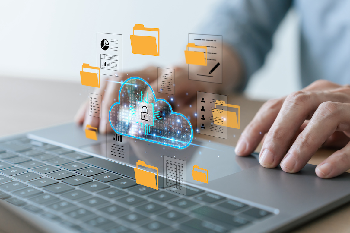 Hands on laptop computer with cloud storage graphic showing file uploads and downloads