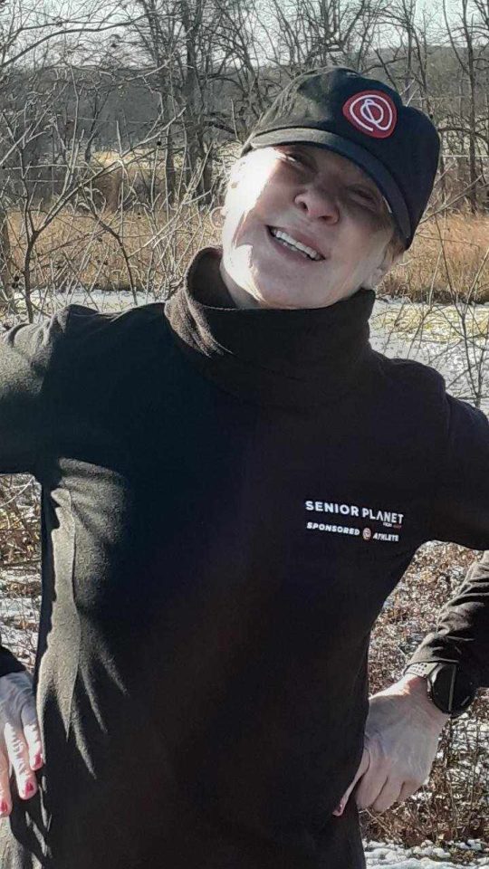 senior woman in black track jacket and matching hat with Senior Planet logos