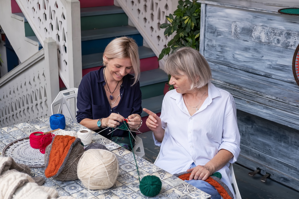 two women crocheting and knitting together with balls of yarn
