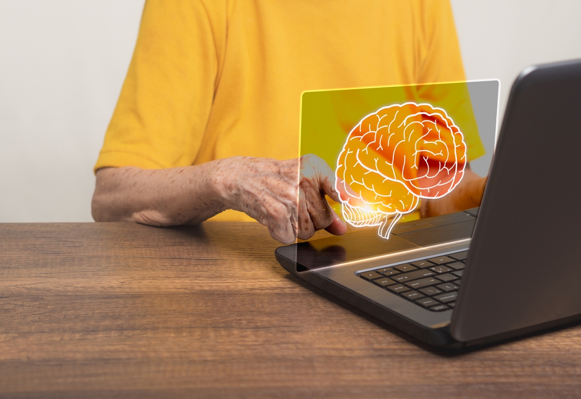 Person sitting in from of laptop looking at a projected Image of a brain.
